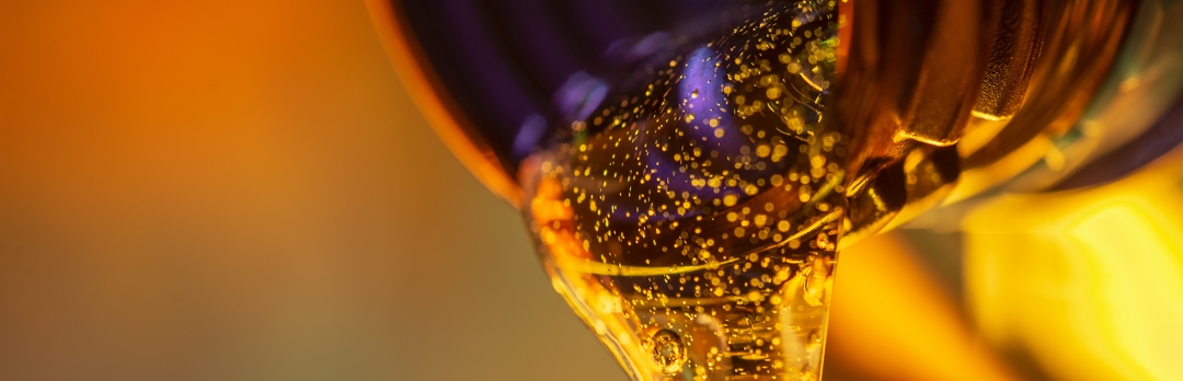 Liquid stream of motor oil flows from the neck of the bottle close-up