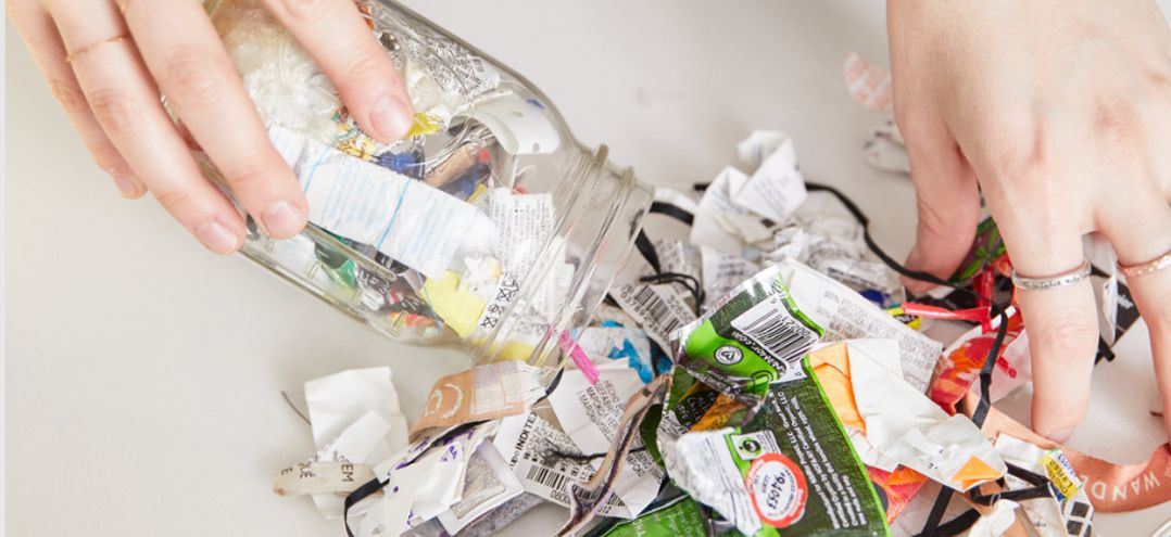 hands displaying trash from a mason jar collected over a one-year time