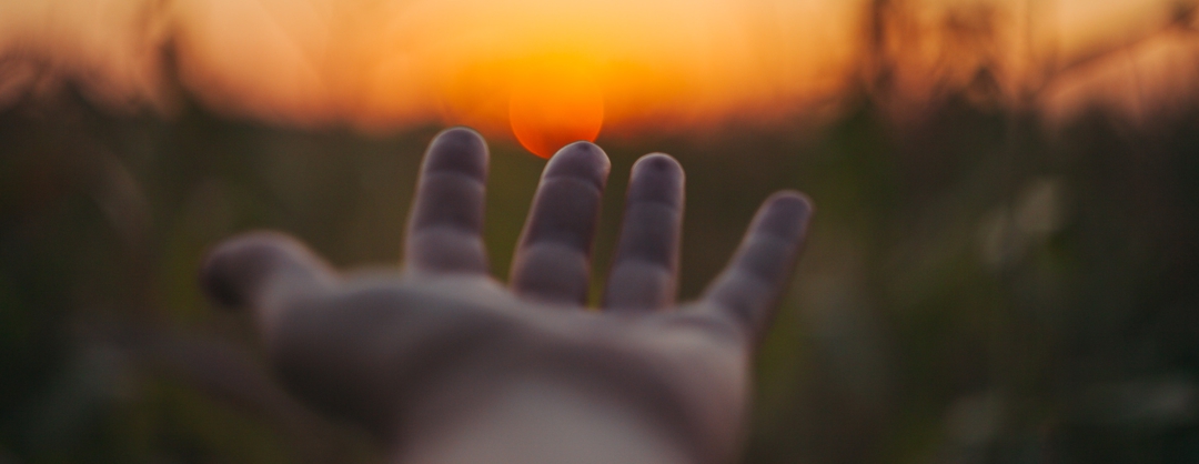 suicide prevention - hand reaching toward setting sun