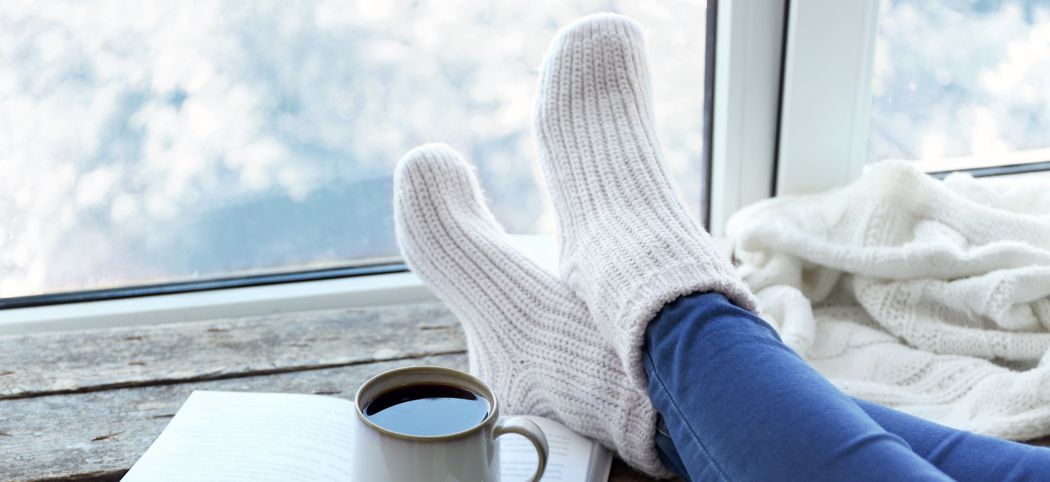 Female legs and hot drink on windowsill