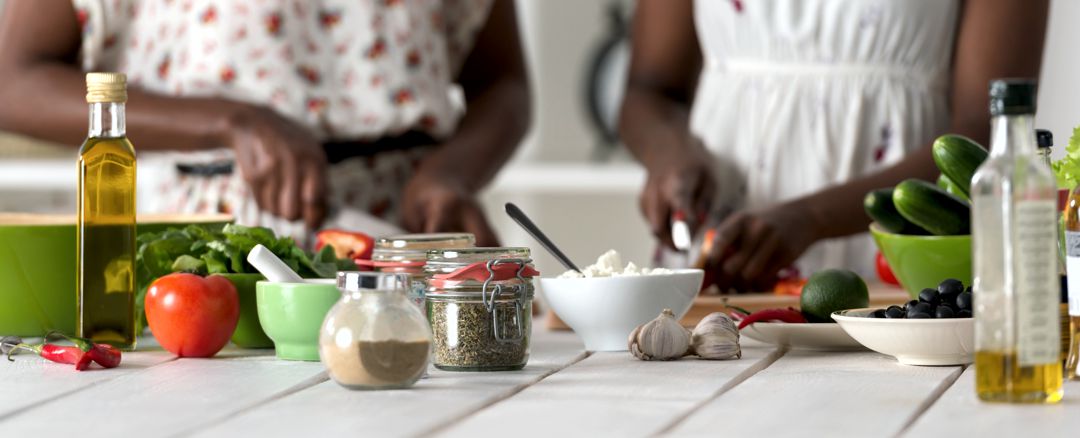 Two women cooking in kitchen making healthy food salad with vegetables