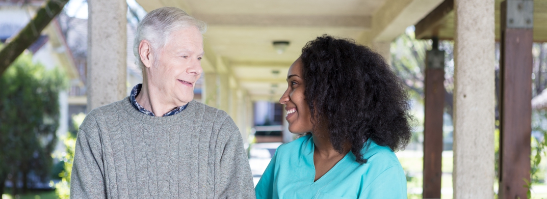 African American nurse assisting elderly man outdoors