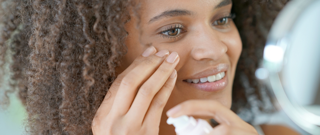 young woman applying lotion to face