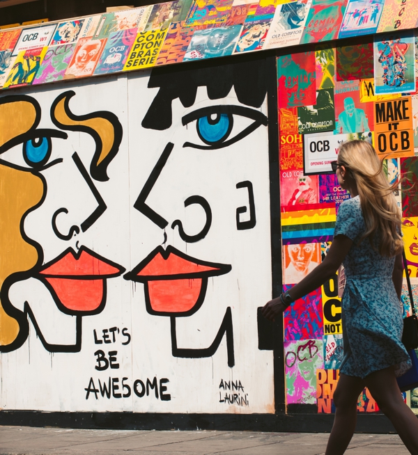 woman walking in front of mural that says "let's be awesome"