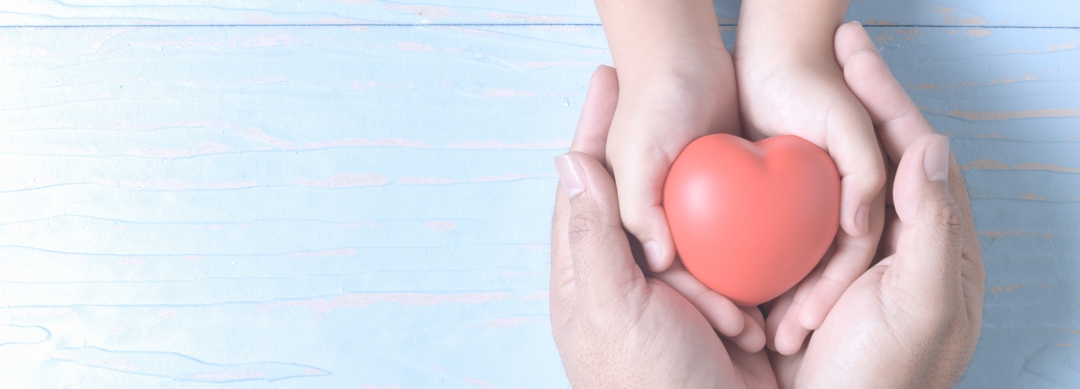 adult and child hands holding red heart on vintage tone, health care, love and family insurance concept, world heart day