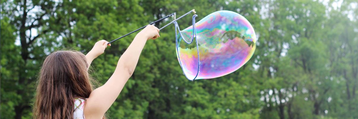 small girl outdoors blowing bubbles