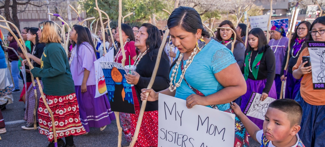 Native American women marching with sign that says My mom, sisters, aunties, and grandma are sacred