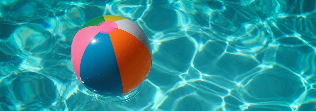 Beach ball floating in outdoor swimming pool