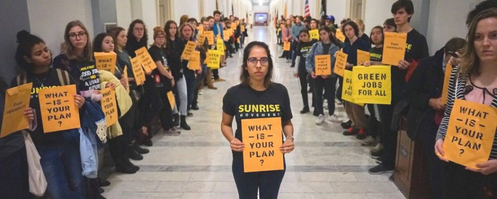 large group of Sunrise Movement youth activists carrying signs that say "What is your plan?"