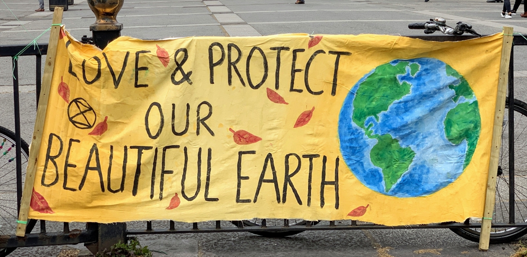 banner hanging on fence that says "preserve and protect our beautiful earth"