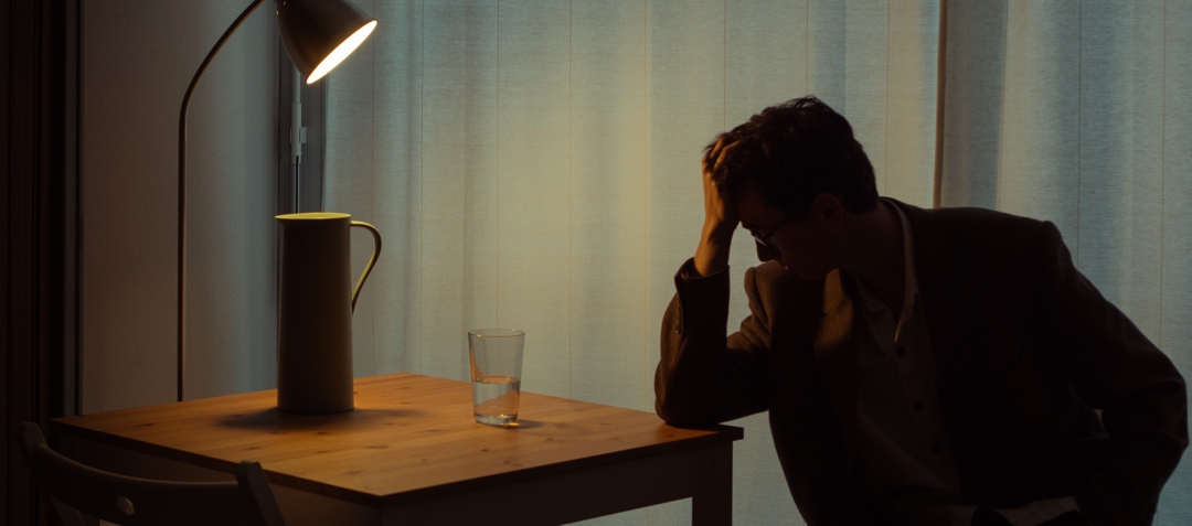 man sitting under dim light with hand resting in hand