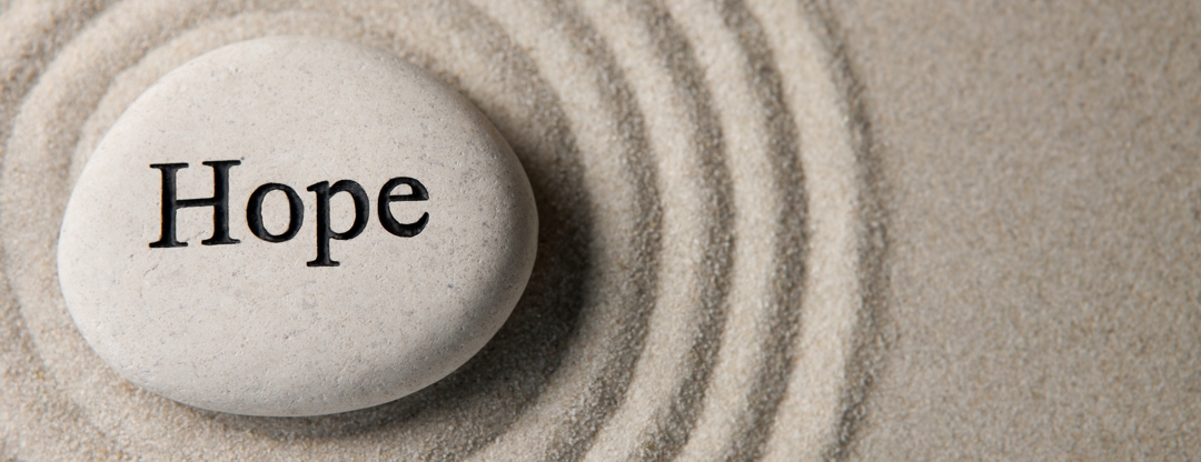 stone in the sand with the word "hope" written on it