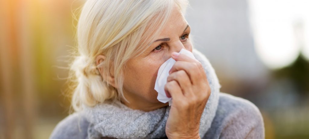 Woman outdoors holding tissue to her nose