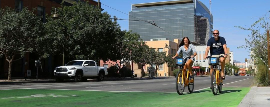 Man and woman riding Tugo Bike Share bicycles downtown Tucson, AZ