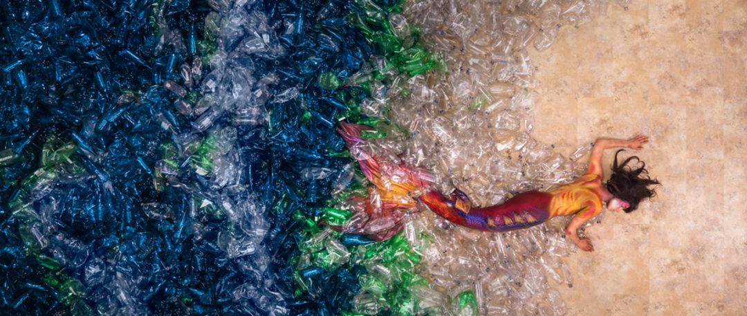 Mermain lying in a pool of empty plastic bottles