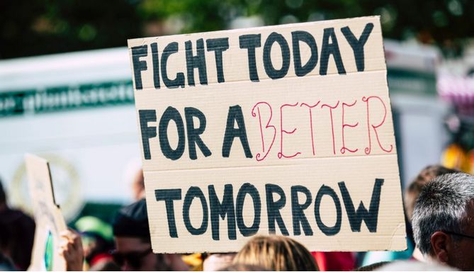 crowd holding sign that says "fight for a better tomorrow"