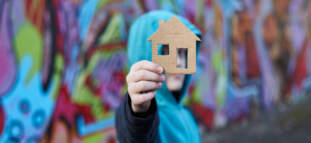 young boy holding a cardboard house