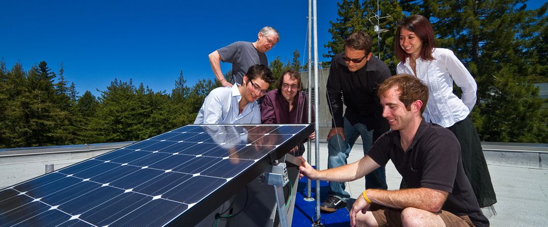 group of men and women on the roof of a home looking at a solar panel