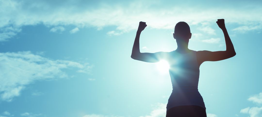Silhouette of woman with arms up displaying strength
