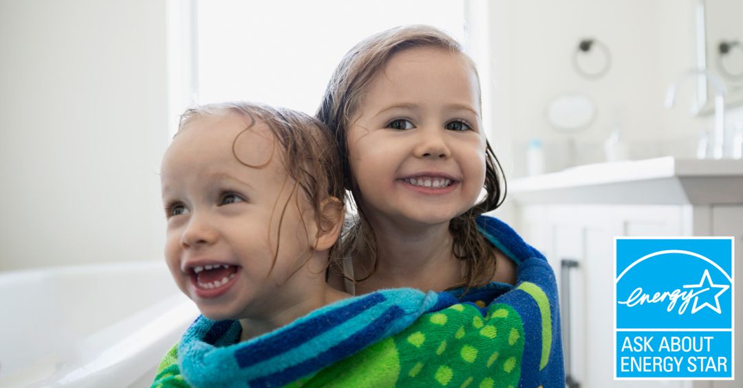 Two little girls wrapped in one big towel after bathing