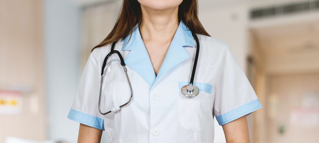 Female health care worker in uniform with stethoscope draped around neck