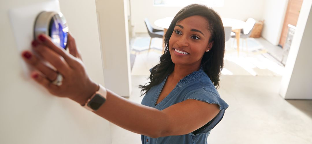 Woman changing dial on thermostat