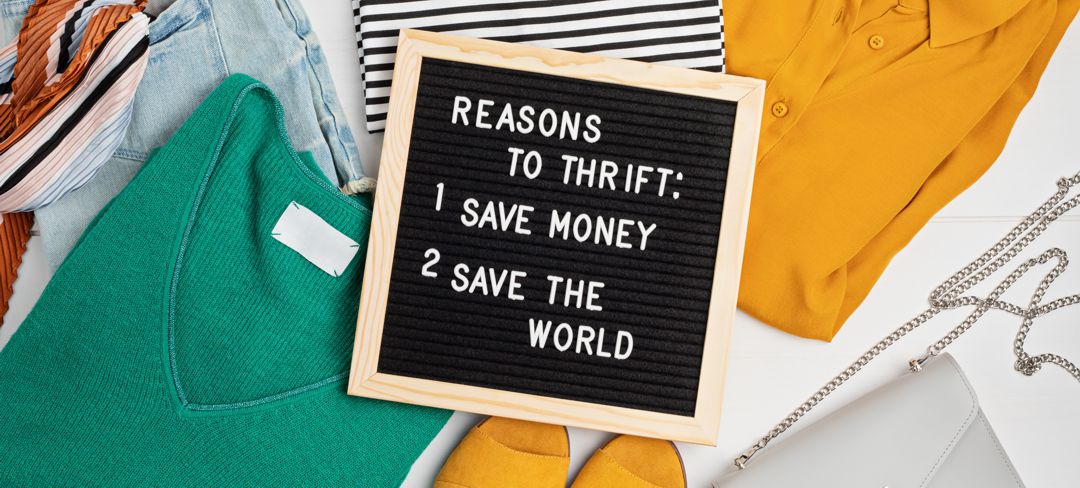 folded clothing with chalk board lying across clothes saying Reason to thrift: save money and save the world