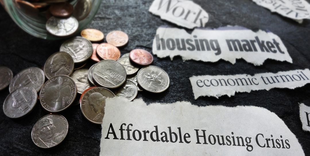 photo of coins next to an open jar that's lying on its side with the words affordable housing crisis, housing market, and economic turmoil