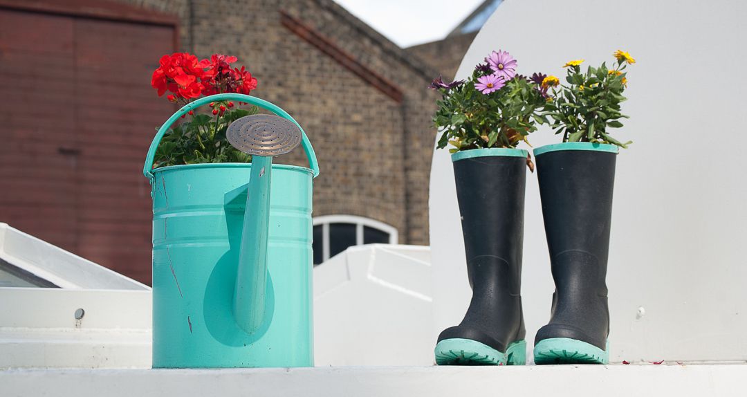 watering can and rubber boots with fresh cut flowers popping out of the top of each