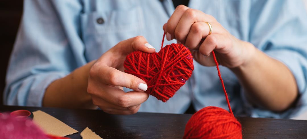 Woman creating red woolen heart