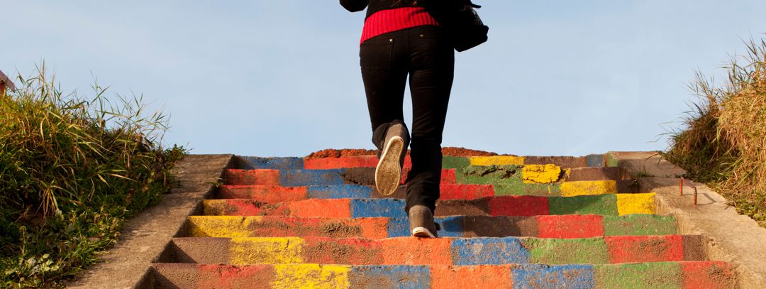 woman running up stairs that are painted in multiple colors