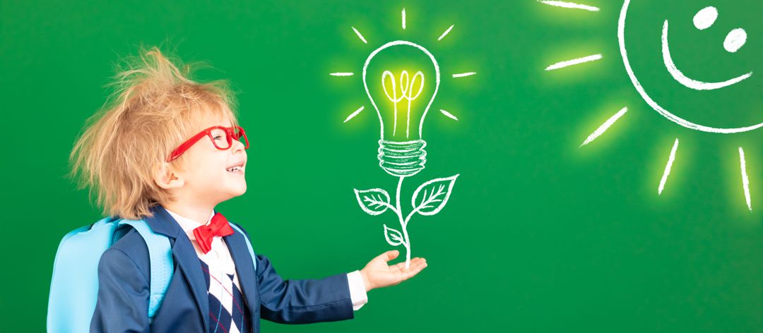 Bright idea! Funny child student with backpack in class. Happy kid against green chalkboard, with LED light bulb drawn on classroom chalk board