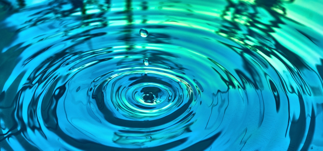 Ripple in pond with blue and green reflections